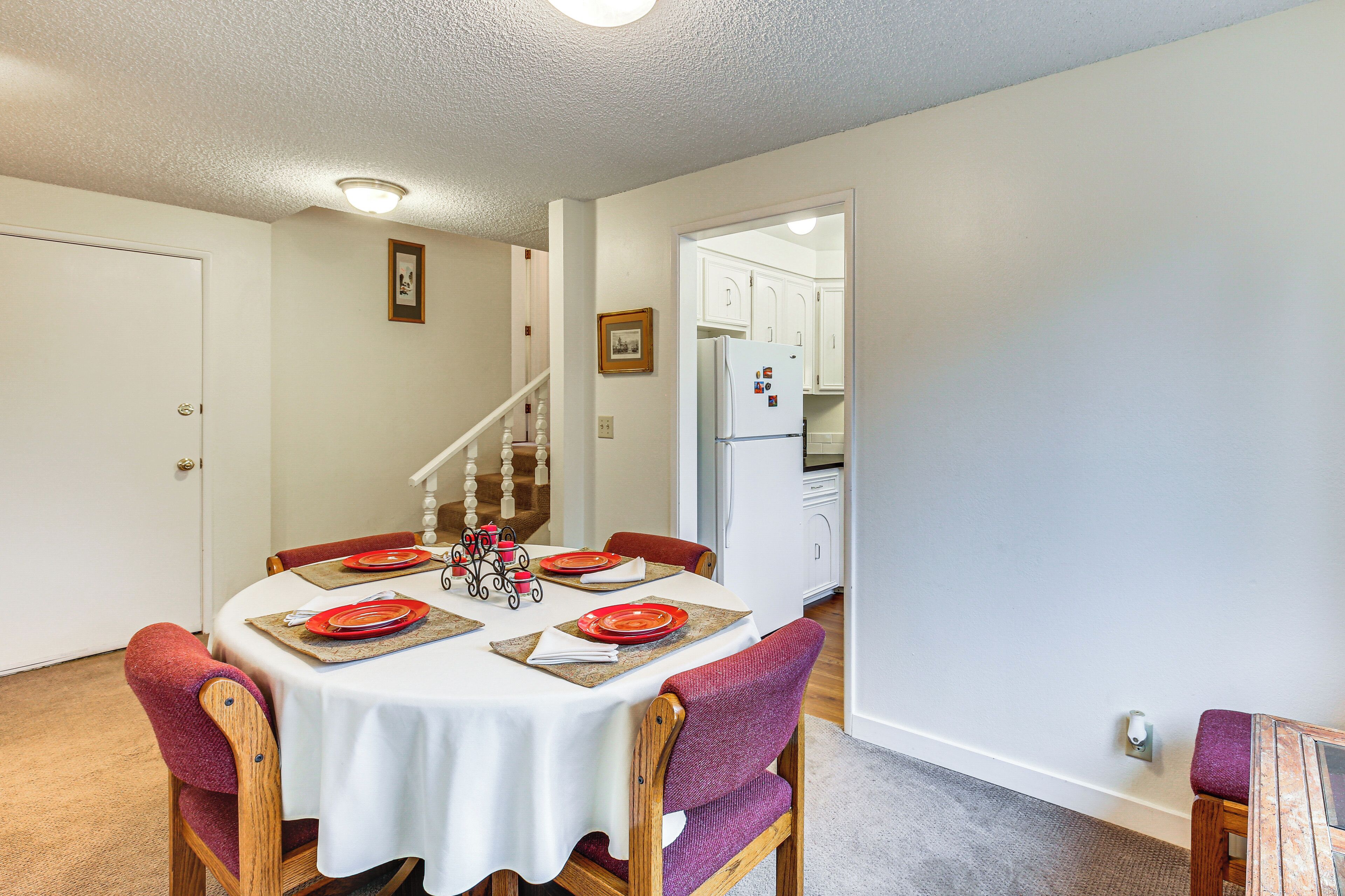 A dining area with a round table set for four, wooden chairs, and a white tablecloth.