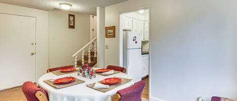 A dining area with a round table set for four, wooden chairs, and a white tablecloth.