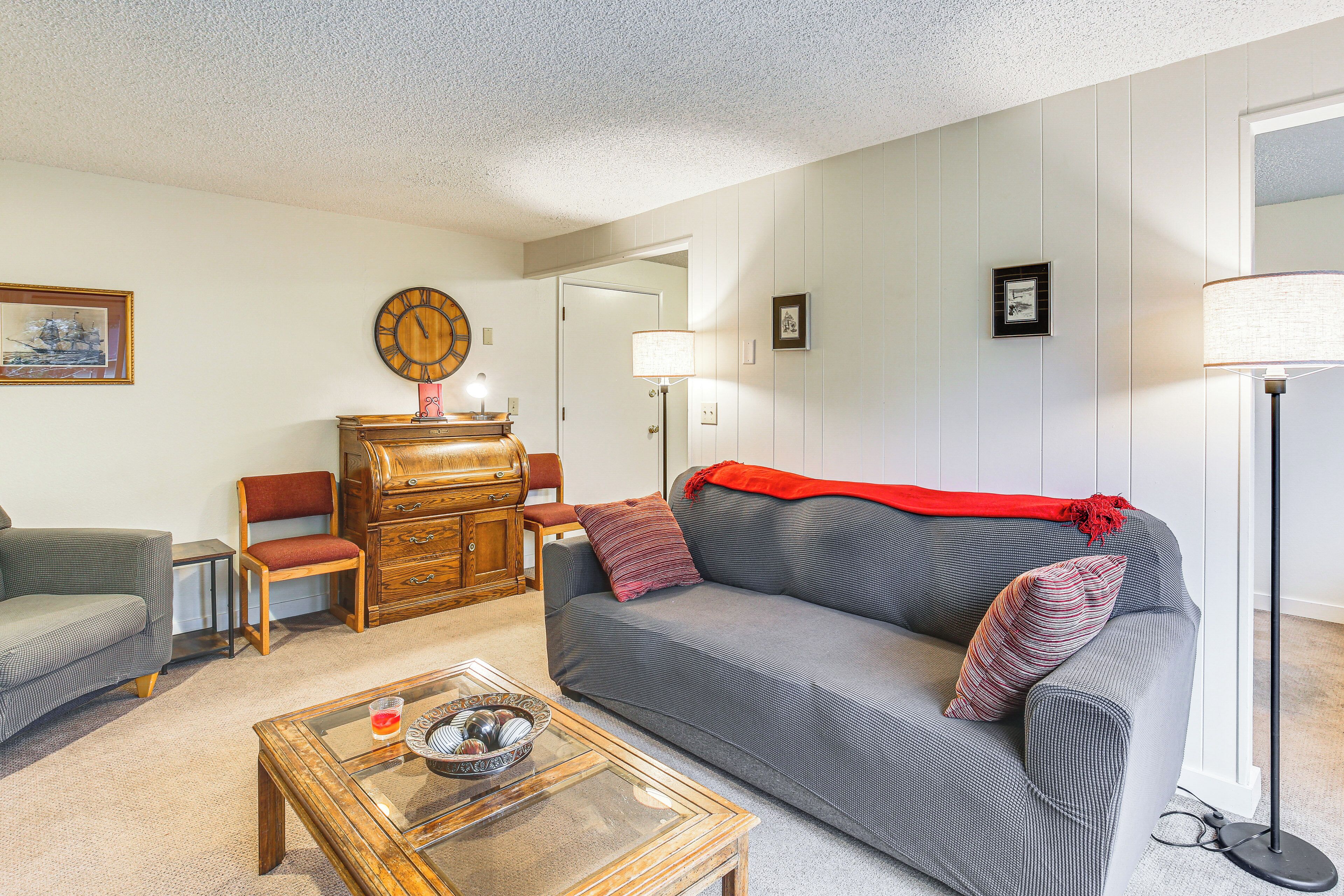 A living room with a grey sofa, wooden dresser, and a glass coffee table.