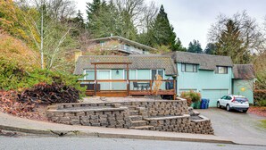 A two-story house with a front porch, a stone retaining wall, and a car parked in the driveway.