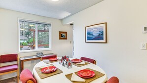 A dining area with a round table set for four, red plates, and a framed picture on the wall.