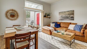 A spacious living room with a wooden dining table, comfortable seating, a sofa, and a large window providing natural light. - 4 Mi to Ocean: Modern Townhome in Wilmington! (Wilmington)