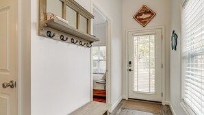 A hallway with a wooden bench, a mirror, and a door with a sign above it. - 4 Mi to Ocean: Modern Townhome in Wilmington! (Wilmington)