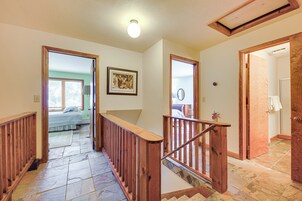 Una escalera con barandillas de madera que lleva a un dormitorio con cama y ventana.