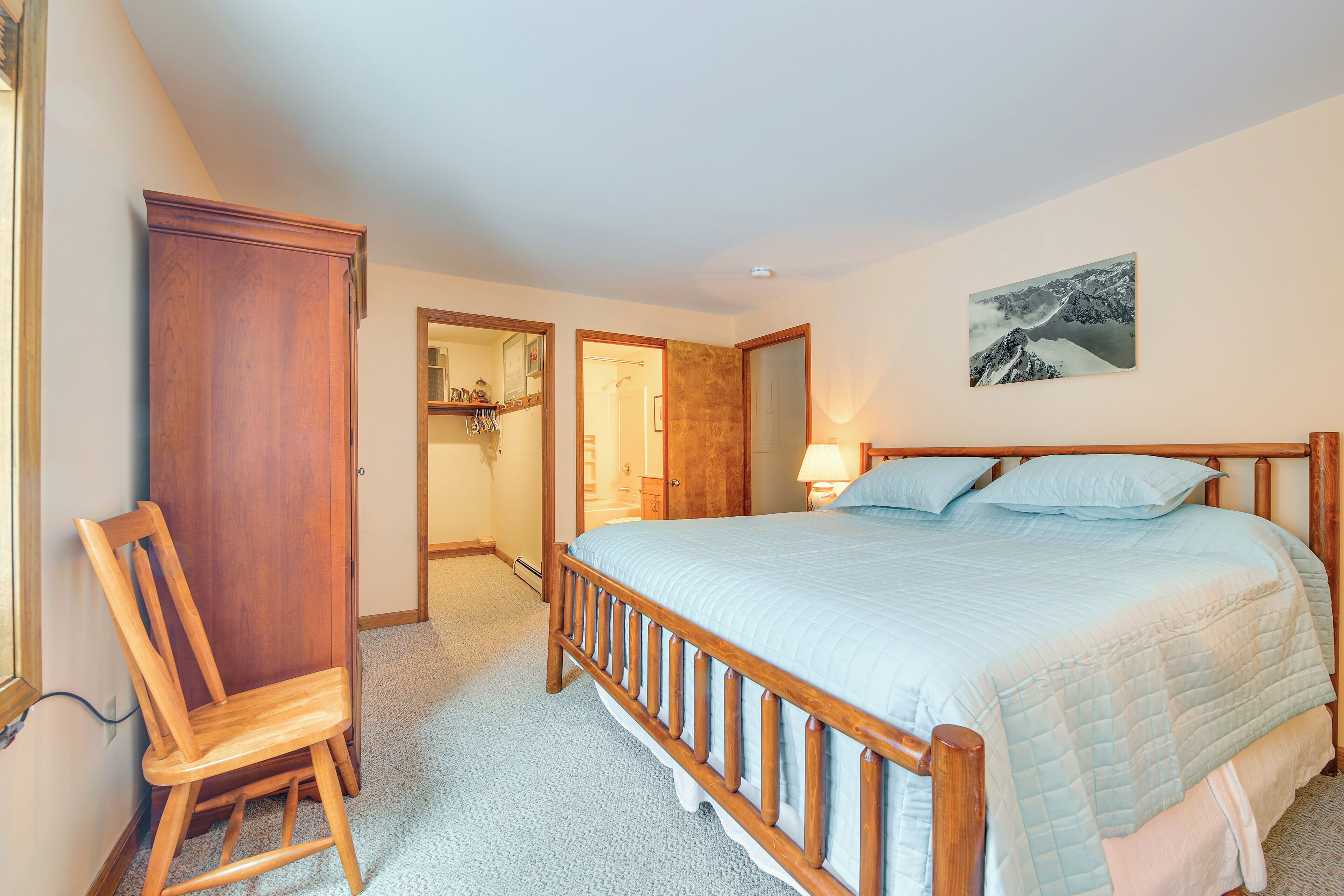 A bedroom with a wooden bed frame, a nightstand, a chair, and a wardrobe.