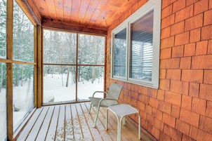 Una terraza de madera con un ventanal de vidrio que da a un área exterior nevada.