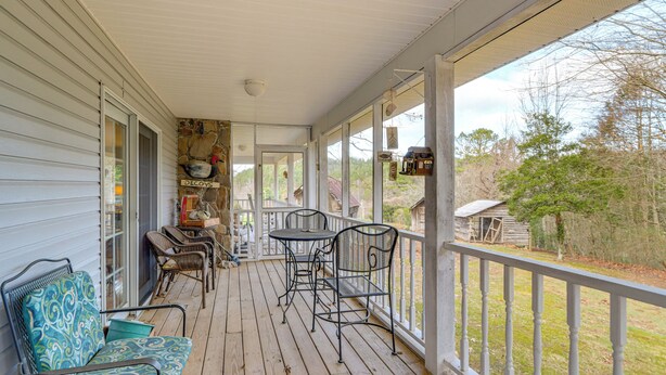 A covered porch with a table and chairs, a small seating area, and a view of the surrounding landscape. - 30 Acres of Mountainside Peace: Home in Marble (Marble)