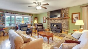 A cozy living room with a stone fireplace, leather chairs, and a television mounted above it. - 30 Acres of Mountainside Peace: Home in Marble (Marble)