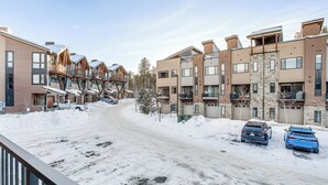 Zona residencial con edificios de varios pisos, una calle cubierta de nieve y coches aparcados.