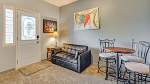 A cozy living room with a dark leather sofa, a small round table, and two matching chairs. A decorative painting hangs on the wall, and a lamp is on a side table. - Hidden Gem in the Heart of Old Town Meridian (Meridian)