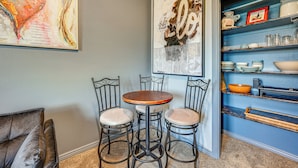 A dining area with a round table and four chairs, a bookshelf with various items, and two large abstract paintings on the wall. - Hidden Gem in the Heart of Old Town Meridian (Meridian)