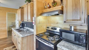 Una cocina con gabinetes de madera, estufa de acero inoxidable, microondas y un lavamanos.