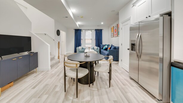 Une cuisine moderne dotée d’un îlot central, d’un réfrigérateur encastré et d’un coin repas avec des chaises et une table.
