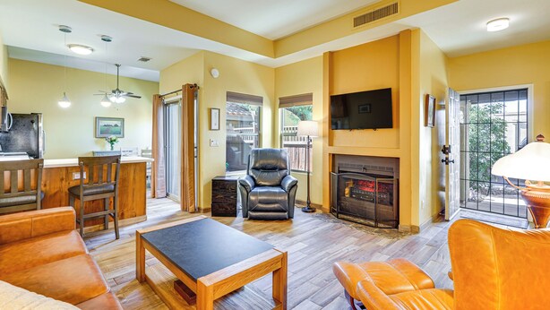 A spacious living room with a fireplace, leather furniture, and a dining area with a kitchen in the background. - 12 Mi to Dtwn Tucson: Tranquil Townhome w/ Office (Tucson)