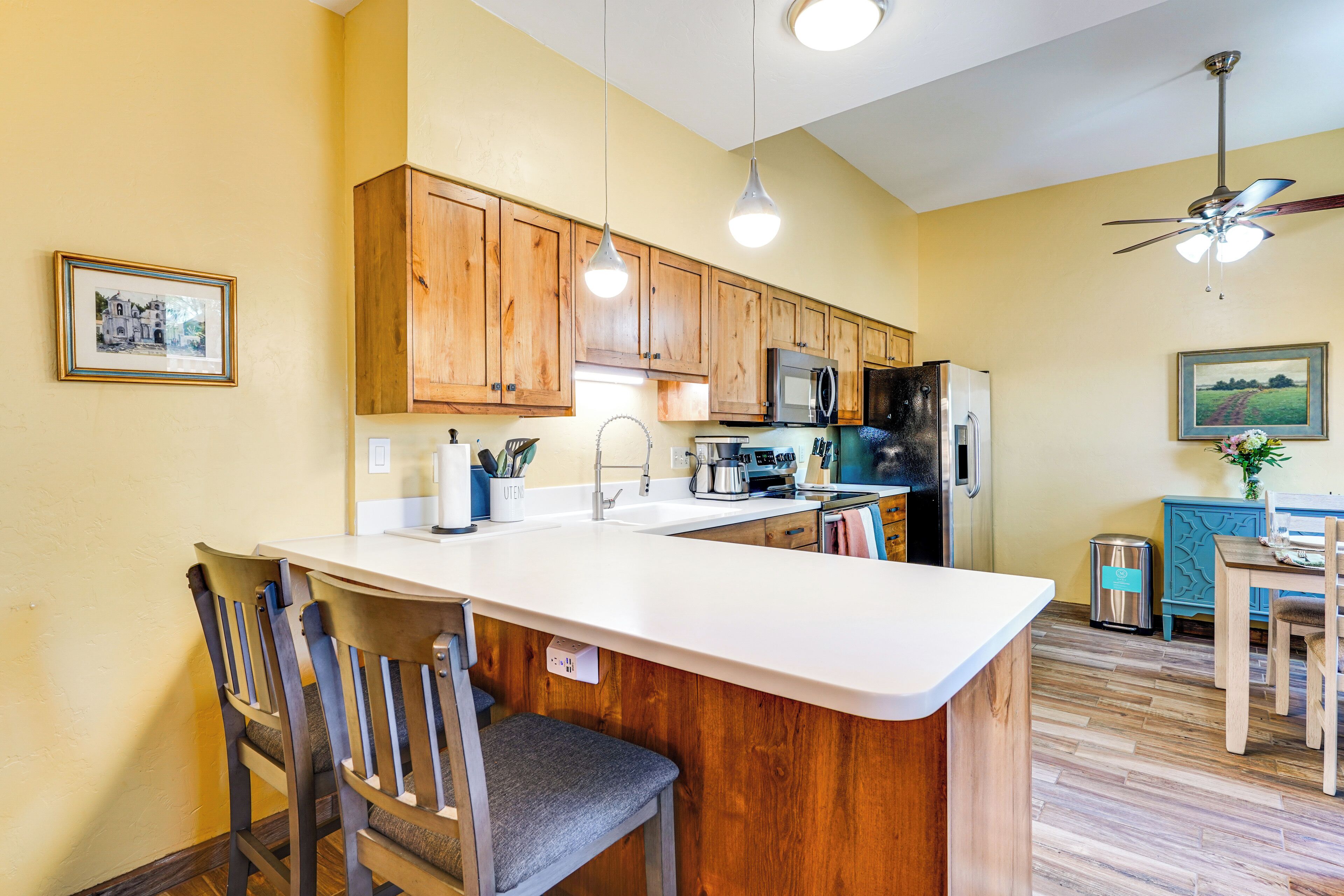 A kitchen with wooden cabinets, a white countertop, and a ceiling fan.