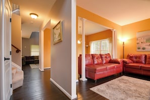 A spacious living room with a red leather sofa, a white column, and a large window.
