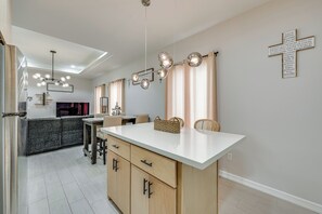 Una cocina moderna con una isla central, iluminación colgante y una cruz en la pared.