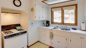 A kitchen with white cabinets, a stove, a sink, and a window with blinds. - Near Hiking: Mtn-view Getaway in Bayfield! (Bayfield)
