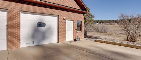A two-story brick building with two garage doors, a small window, and a concrete driveway.