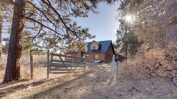 A rustic house with a metal gate, surrounded by dry grass and pine trees. - Near Hiking: Mtn-view Getaway in Bayfield! (Bayfield)