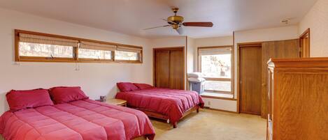 A bedroom with two beds, a ceiling fan, and a window with blinds.
