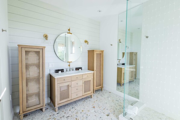 A bathroom with a wooden vanity, a round mirror, and a glass shower enclosure. - Starlight Serenity - Hideaway w Stunning Views (Summerland Key)