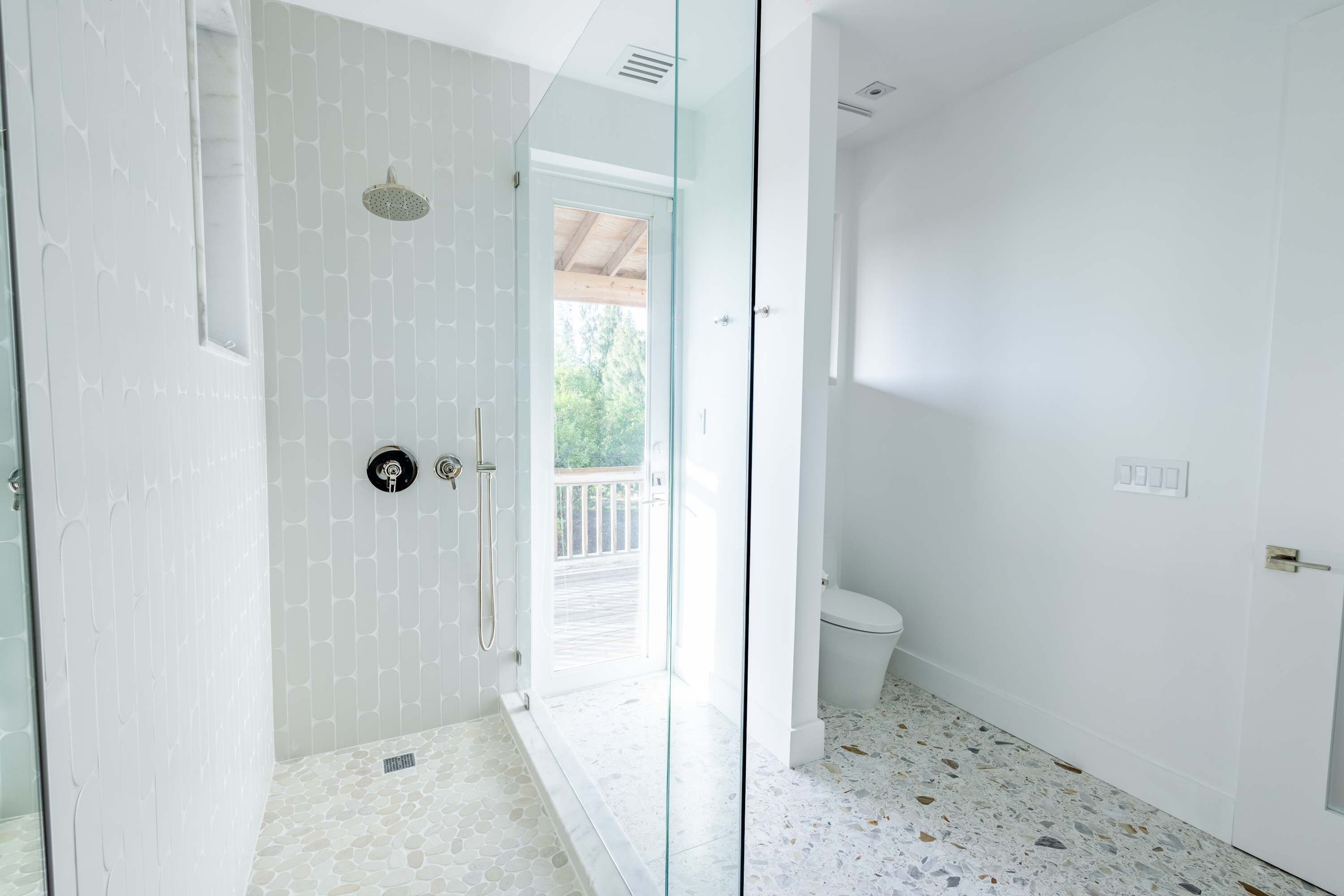 Un baño moderno con cabina de ducha de vidrio, inodoro y vistas al balcón.