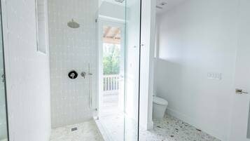 Un baño moderno con cabina de ducha de vidrio, inodoro y vistas al balcón.