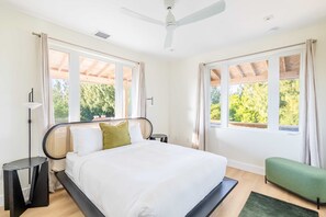 A modern bedroom with a large bed, two windows, a ceiling fan, and a green bench. - Starlight Serenity - Hideaway w Stunning Views (Summerland Key)
