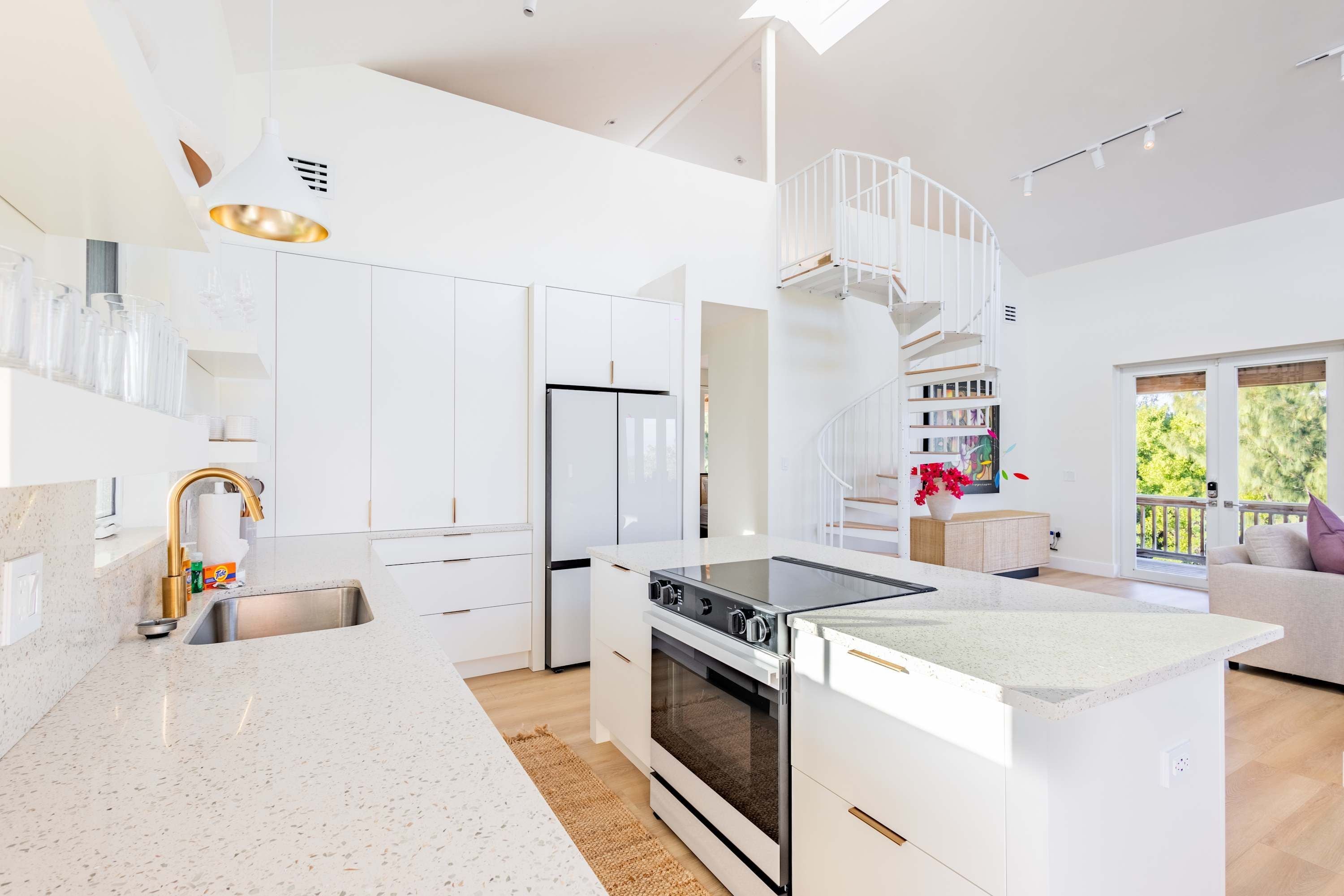 Una cocina moderna con armarios blancos, una isla central, horno empotrado y un refrigerador de acero inoxidable.