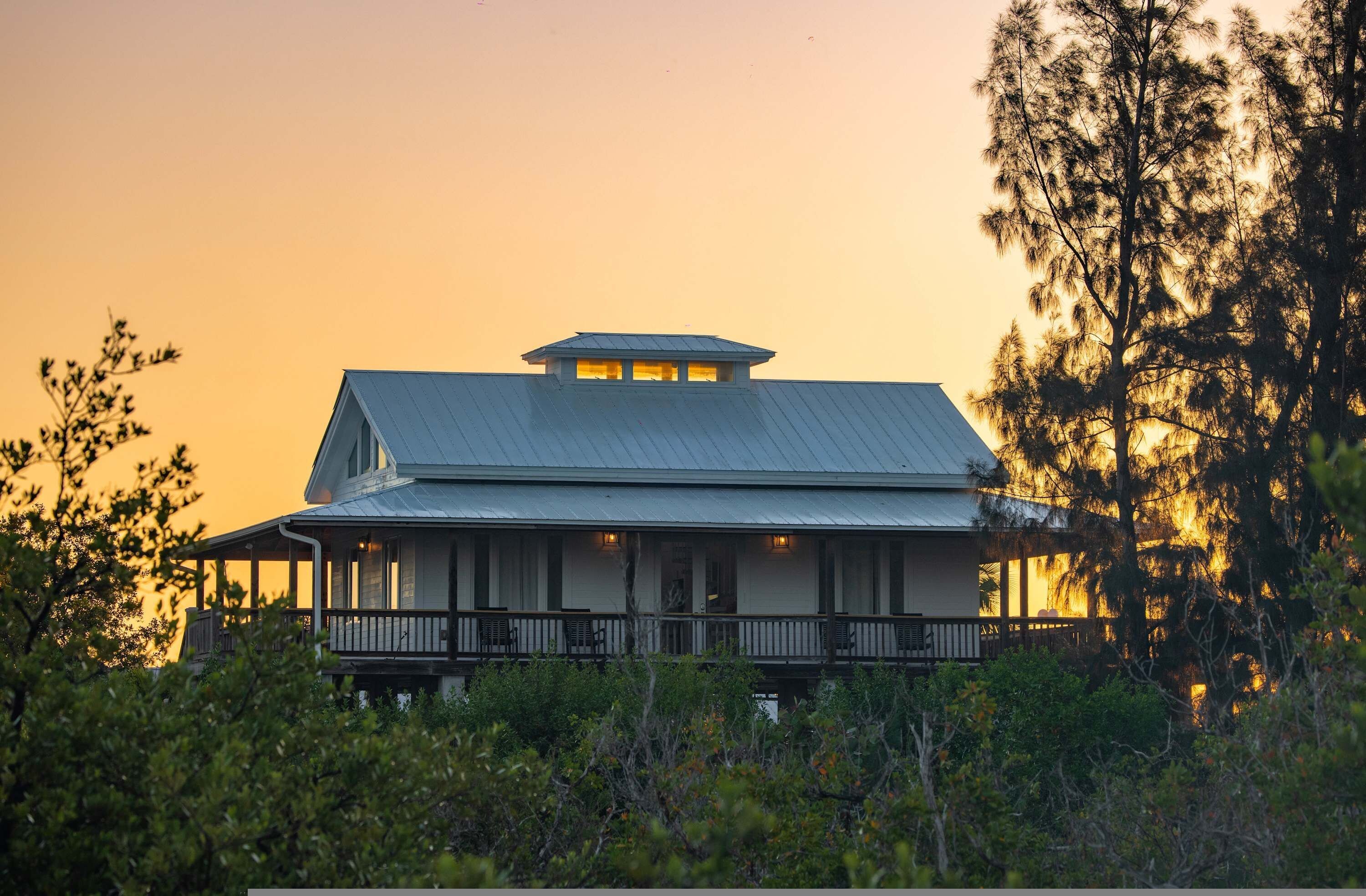 A two-story house with a balcony, surrounded by trees and vegetation.