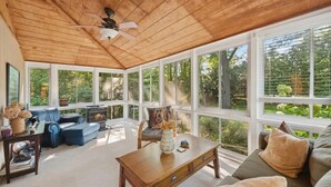 A sunroom with a wooden ceiling, large windows, a fireplace, and a seating area with a sofa and a table. - Cozy pet-friendly cottage near Lake Michigan (Grand Beach)