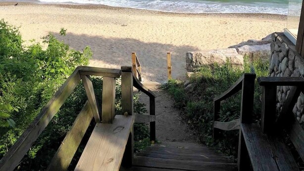 A wooden staircase leading to a beach with a clear view of the ocean. - Cozy pet-friendly cottage near Lake Michigan (Grand Beach)