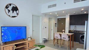 Una sala de estar moderna con televisión de pantalla plana, muebles de madera, una mesa de centro y un sofá gris.