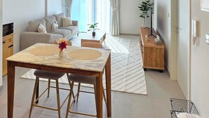 Una sala de estar moderna con comedor, un sofá, una mesa de centro y un televisor.