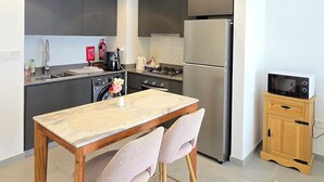 Una cocina moderna con comedor, que incluye un refrigerador de acero inoxidable, un microondas y una estufa a gas.