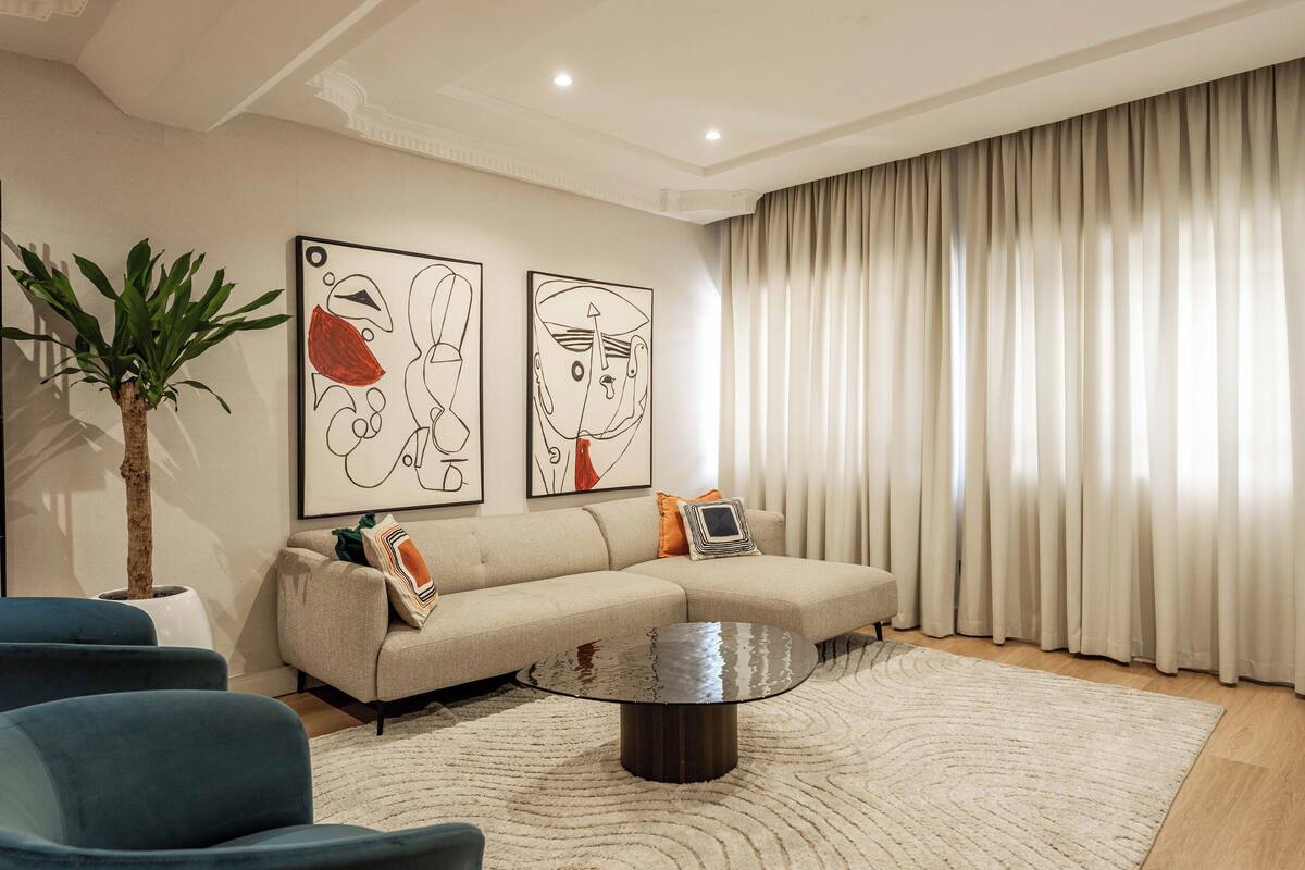 A modern living room with a sectional sofa, a round coffee table, and abstract wall art.