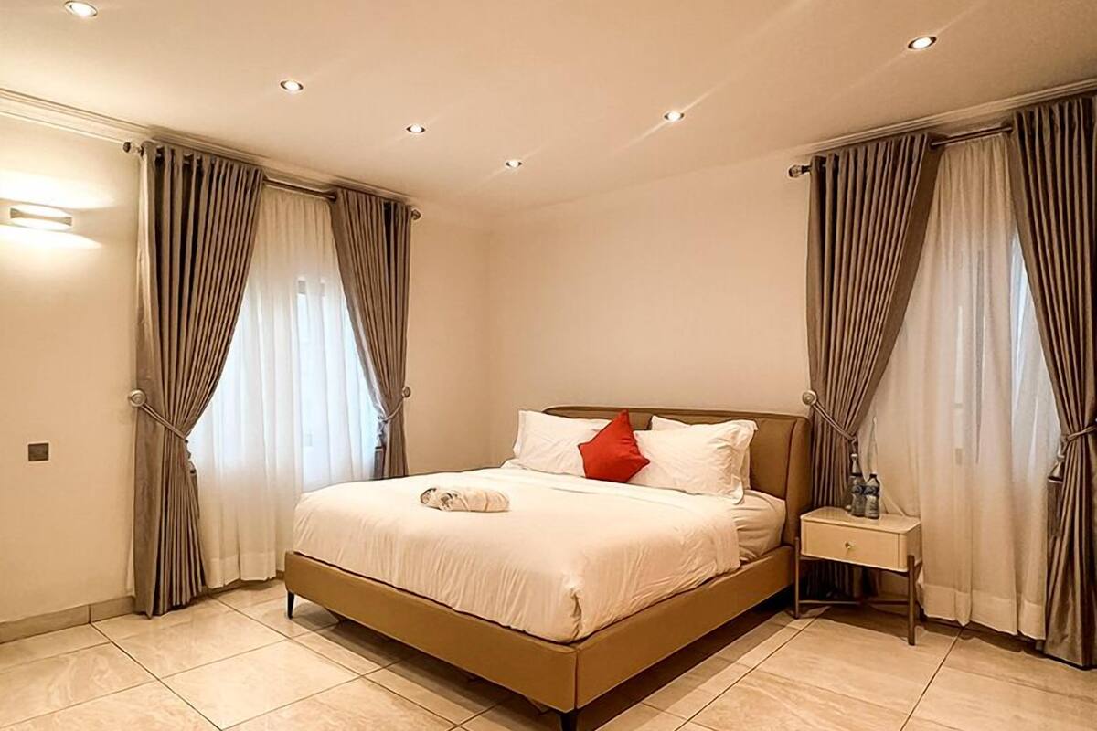 A modern bedroom with a large bed, a bedside table, and curtains.