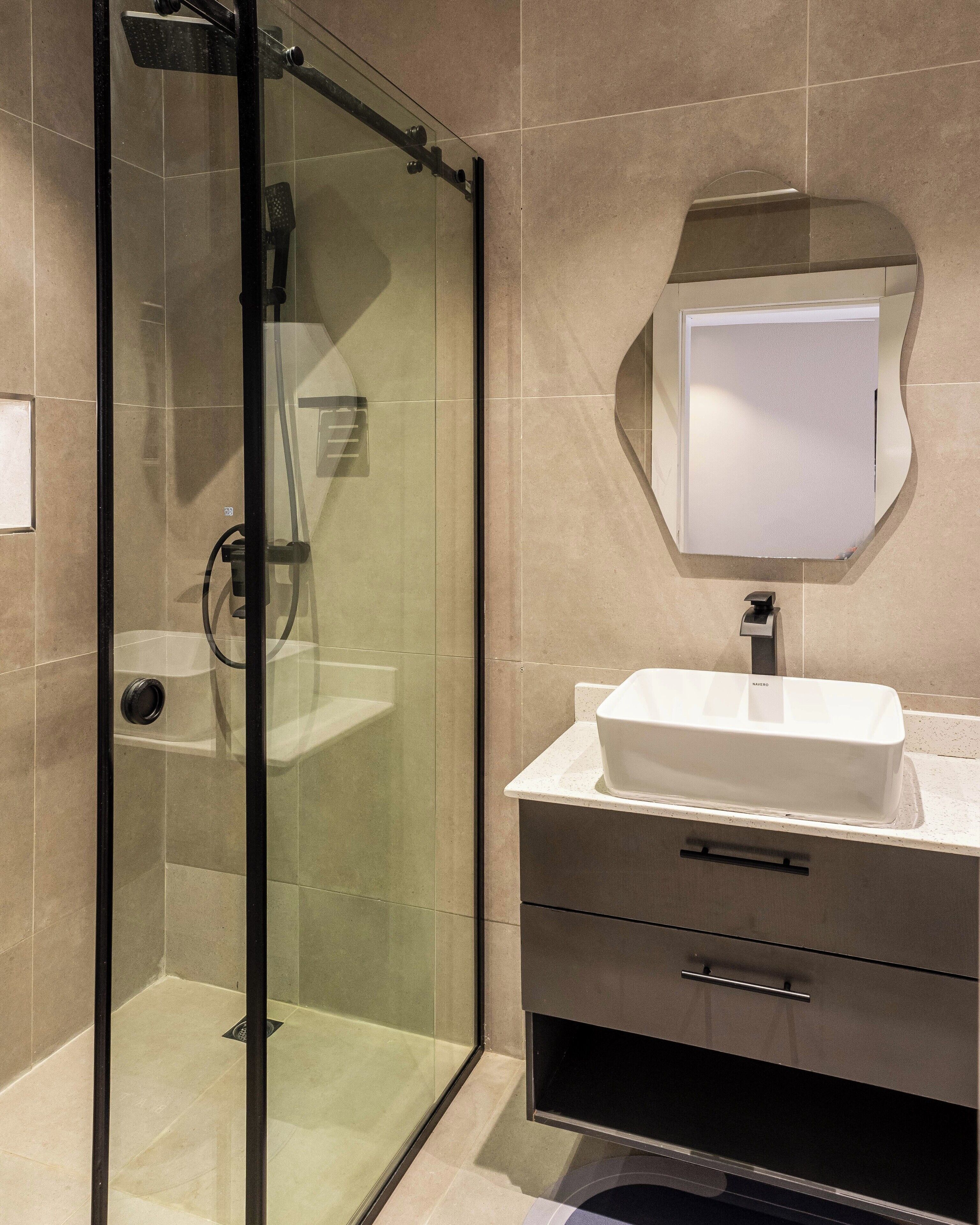 A modern bathroom with a glass-enclosed shower, a white sink, and a mirror above it.
