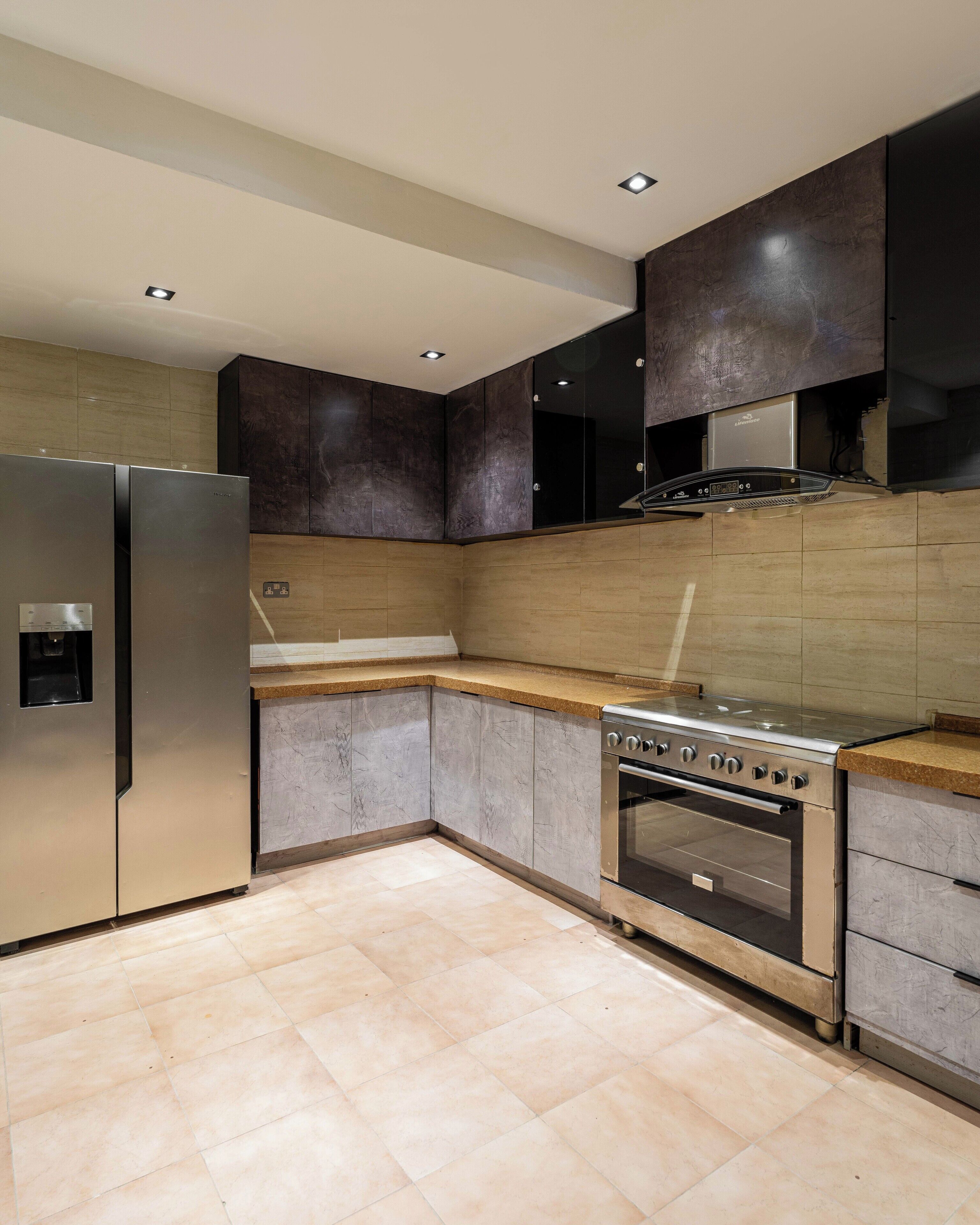 Una cocina moderna con electrodomésticos de acero inoxidable, horno empotrado y muebles oscuros.