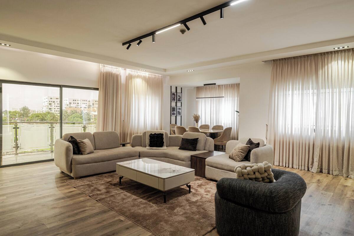 A spacious living room with a sectional sofa, a coffee table, and a grey armchair.