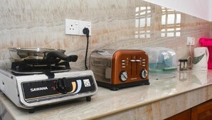 Une cuisine équipée d’une cuisinière, d’un grille-pain et d’une machine à café, le tout posé sur un plan de travail en marbre.