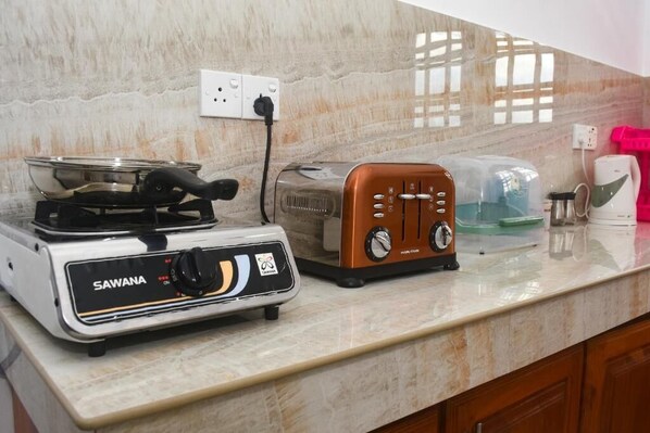 A kitchen with a stove, toaster, and coffee maker on a marble countertop. - Ravi Villa (Hikkaduwa)