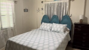 Ein Schlafzimmer mit einem Bett, einem Schminktisch und einem Fenster mit Vorhängen.
