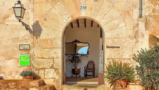 An entrance with a stone archway, a reception desk, and a potted plant. - Finca Son Valls (Felanitx)