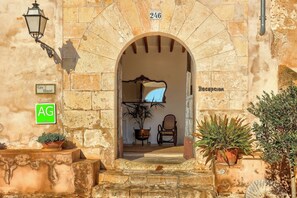 An entrance with a stone archway, a reception desk, and a potted plant. - Finca Son Valls (Felanitx)