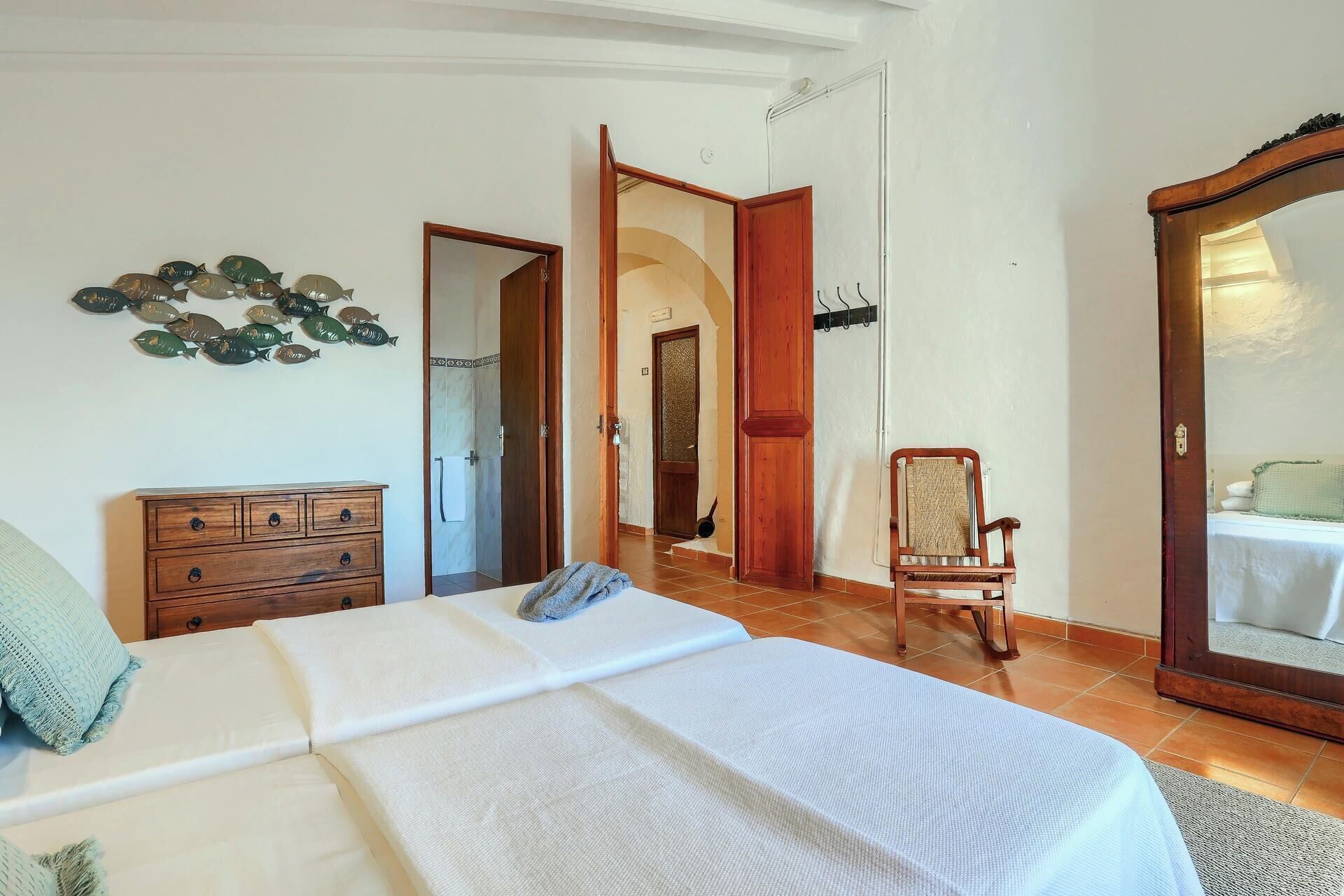 A bedroom with a bed, wooden dresser, chair, and a large mirror.