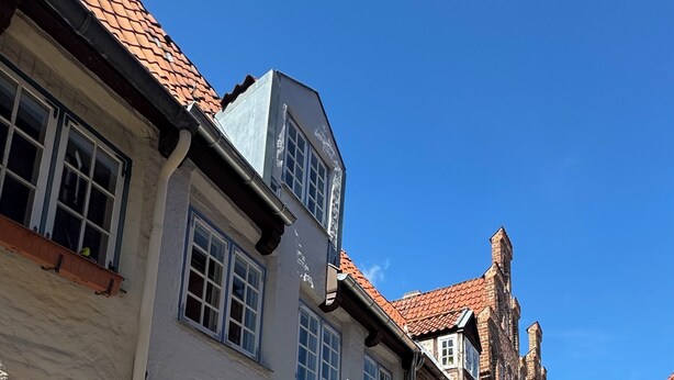 A cobblestone street lined with historic buildings featuring traditional European architecture, including gabled roofs and brick facades.