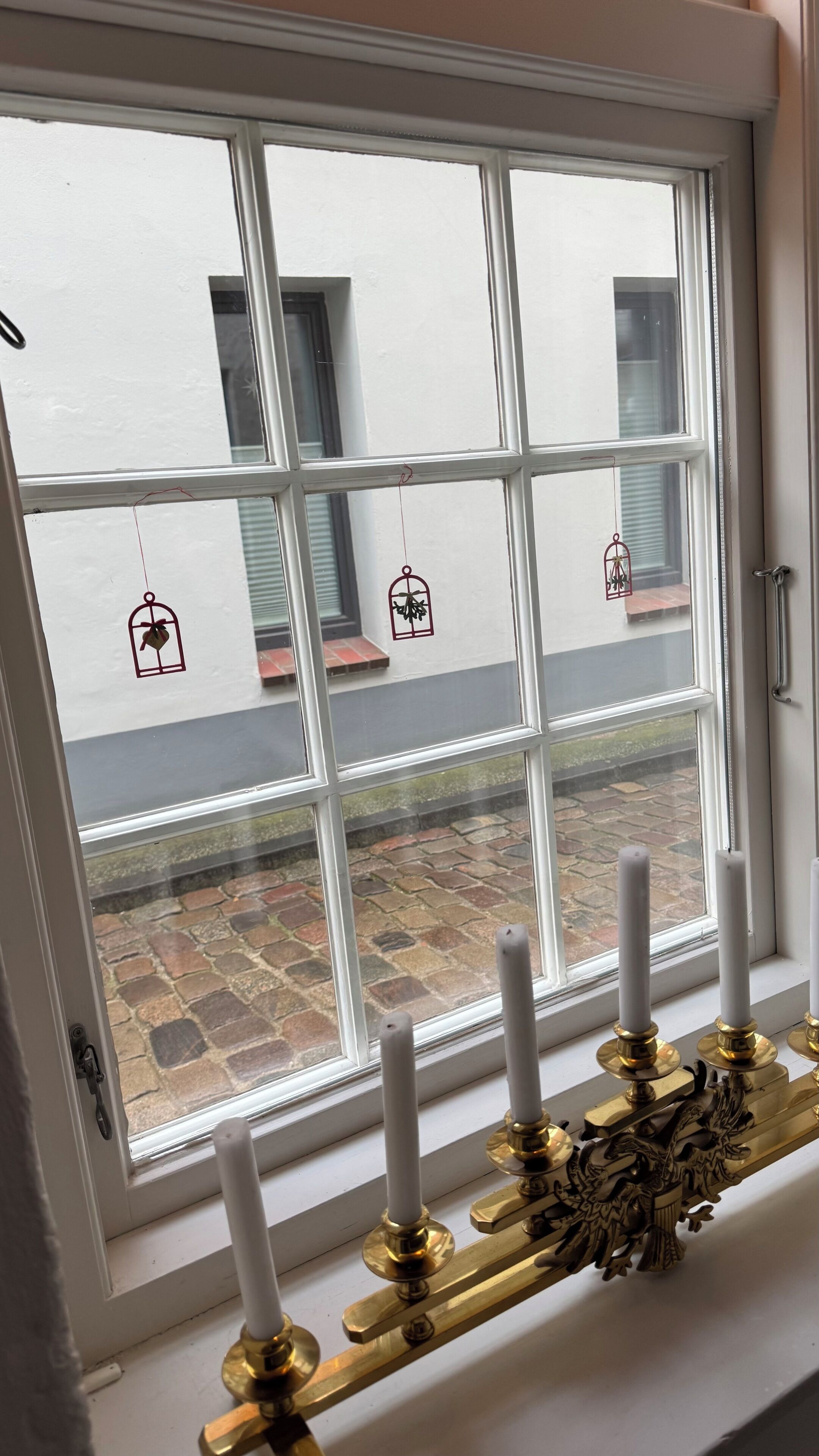 A window with a white frame and a view of a stone-paved courtyard.