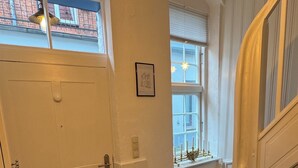 A staircase with a landing leading to a door, a window with a view, and a light fixture above.